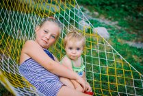 Meninas adolescentes e criança se divertindo no jardim em uma rede — Fotografia de Stock
