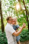 Портрет отца и дочери, танцующих вместе в лесу — стоковое фото