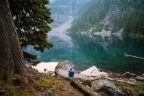 Чоловік сидить поруч з альпійським озером в каскадах — стокове фото