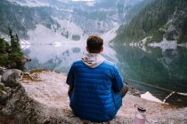 Hombre sentado junto al lago alpino azul en las cascadas - foto de stock