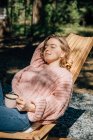 Mujer con taza de café relajándose en el bosque. - foto de stock