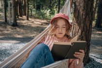 Mujer en libro de lectura de hamacas en el bosque, primer plano. - foto de stock