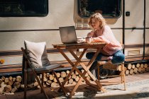 Étude femme avec ordinateur portable près de remorque à l'extérieur. — Photo de stock
