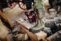 Primo piano degli stivali da lavoro di un uomo. Taglio legna da ardere con catena — Foto stock