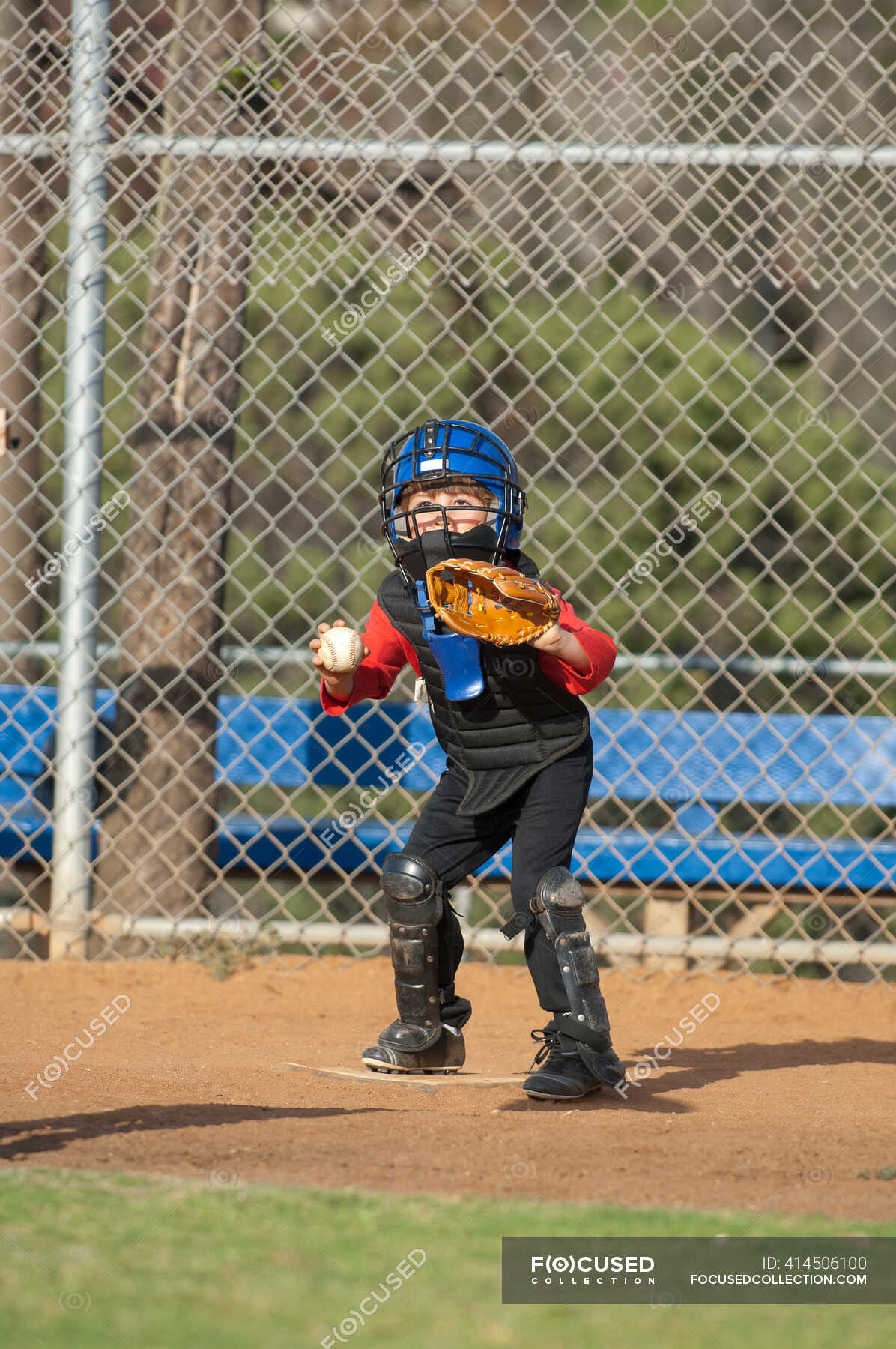 Young boy in catchers gear waiting at home plate to tag out a runner