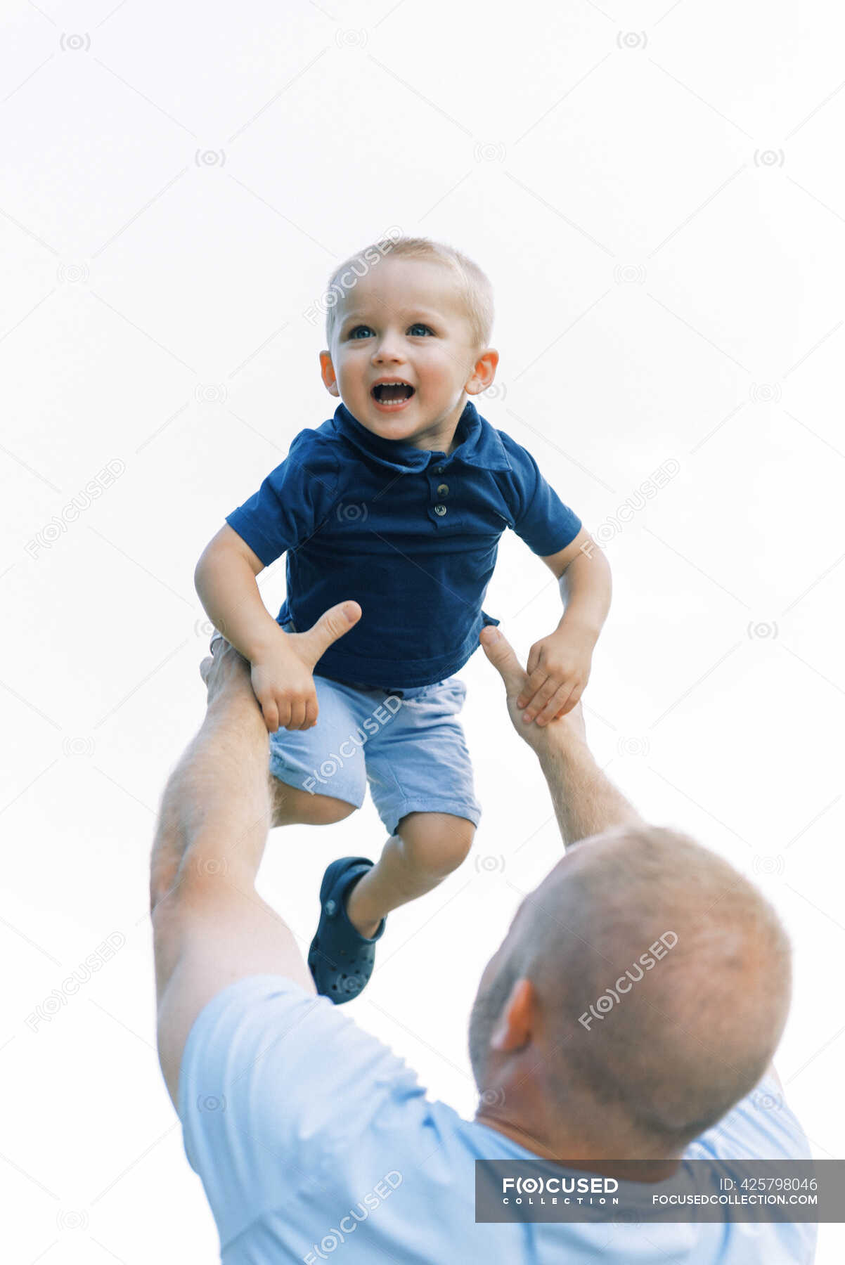 A father throwing his son into the air during playtime outside — lean, bonding Stock Photo