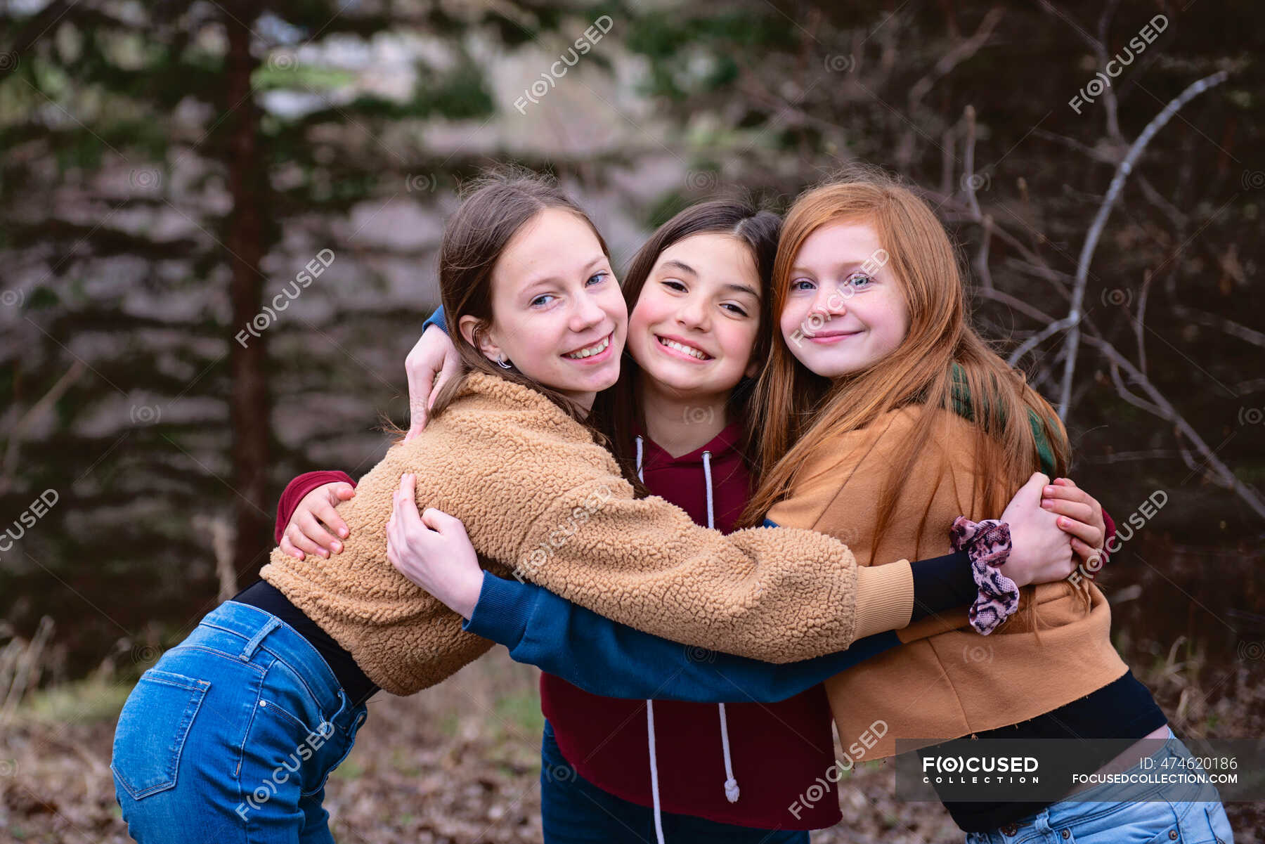 Three tween girls standing outdoors hugging each other. — feminine ...