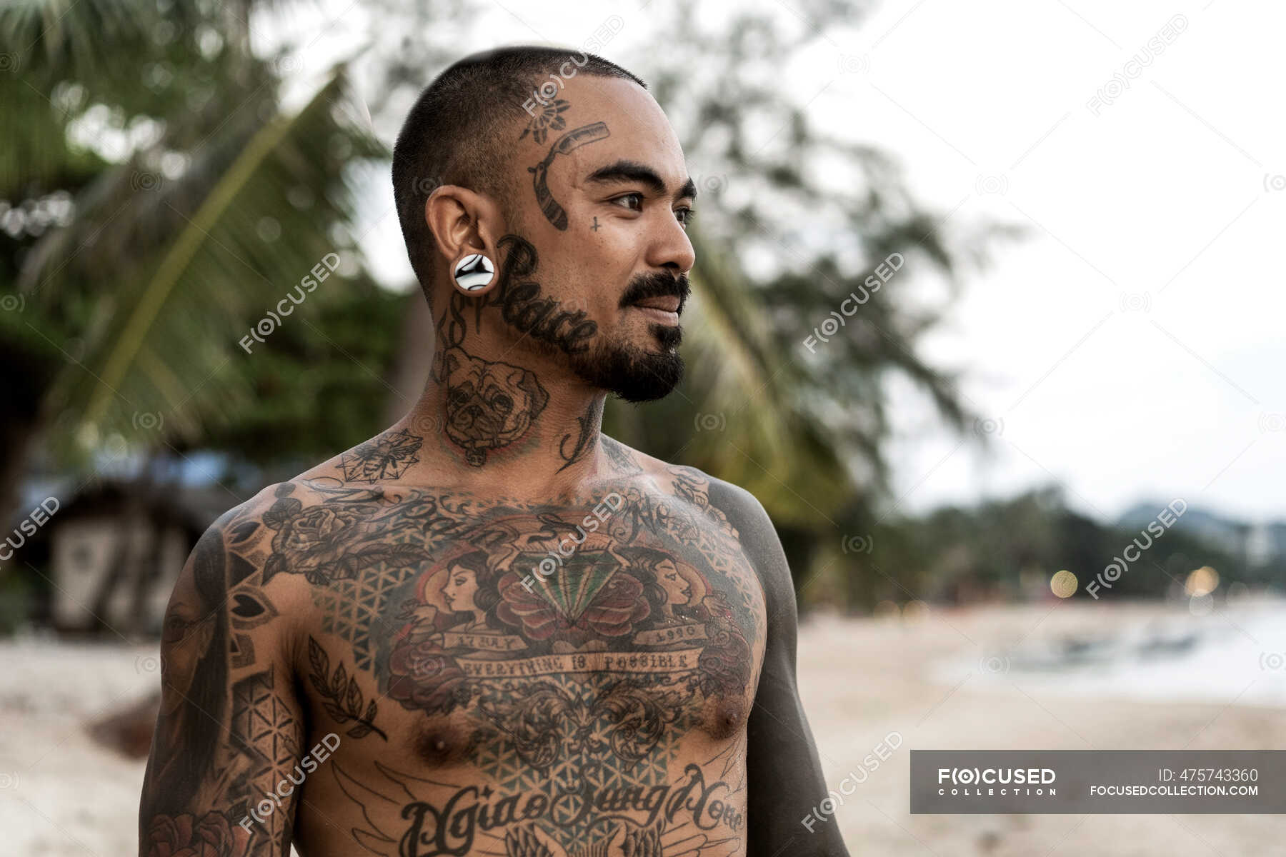 Thai guy on the seashore among the palm trees all in tattoos — studio, one - Stock Photo