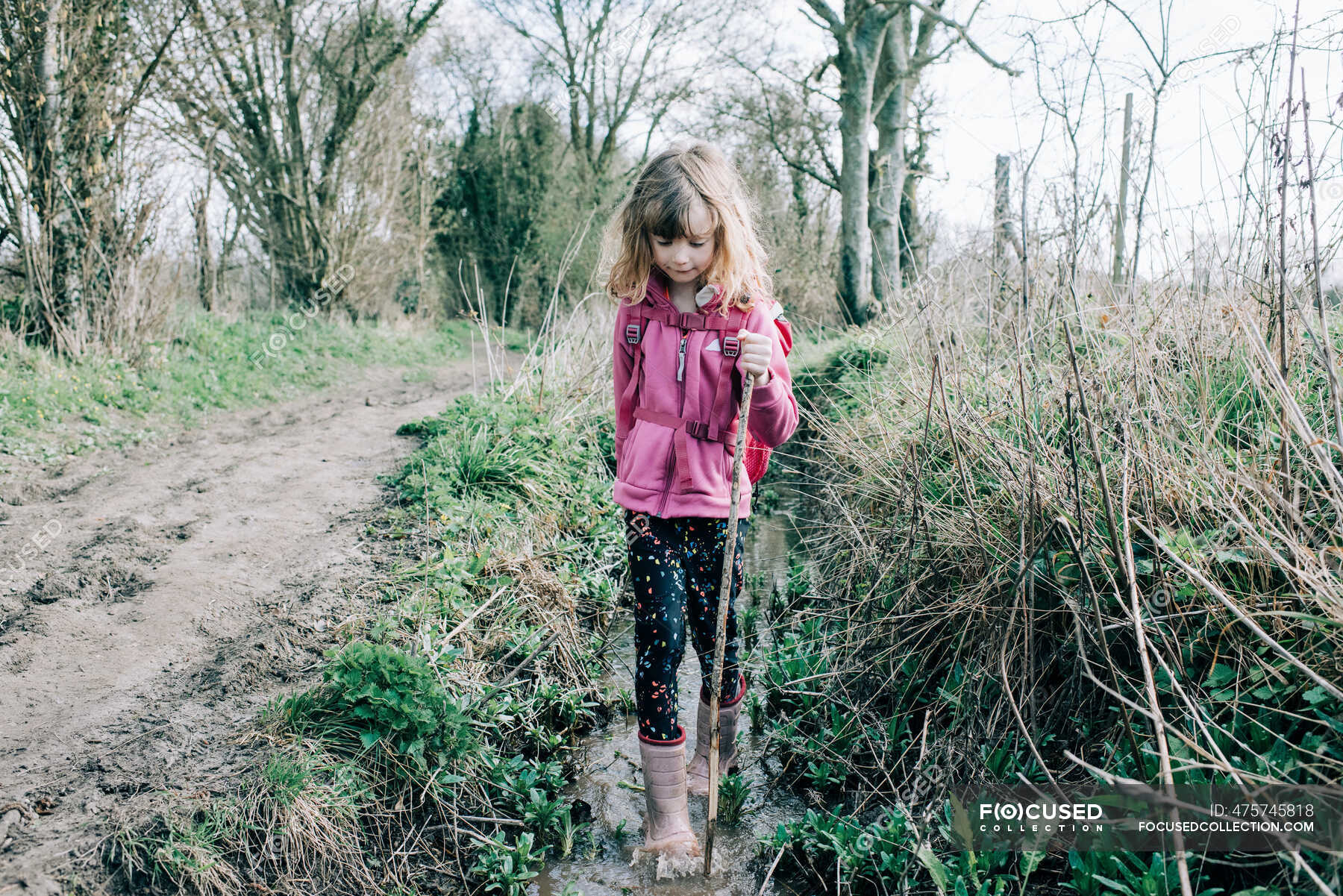 Young girl walking through a stream exploring whilst hiking in the UK ...