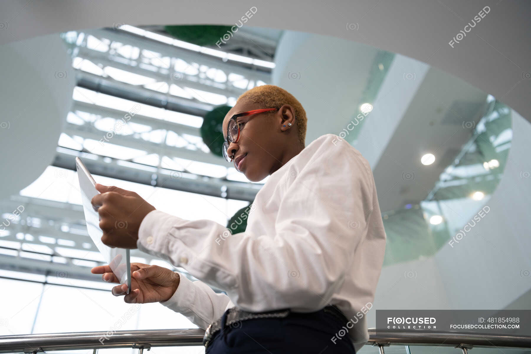 Black Female Clerk In Glasses Browsing Digital Tablet During Work In