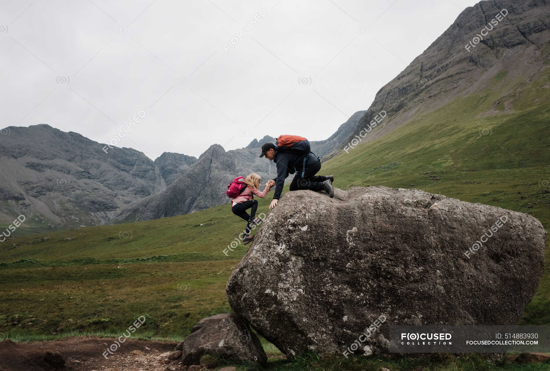 Dad helping his daughter climb whilst hiking the Scottish Highlands ...