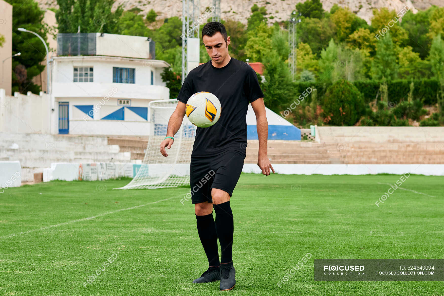 A football player touches a soccer ball on a soccer field — active