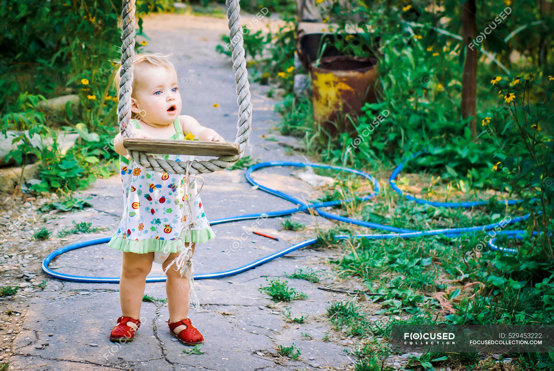 cute-baby-girl-3-4-year-old-in-the-garden-plays-a-rustic-swing