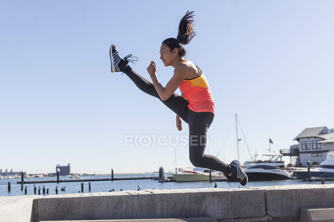 Photographie de femme en forme exécutant coup de pied sautant — Photo de stock