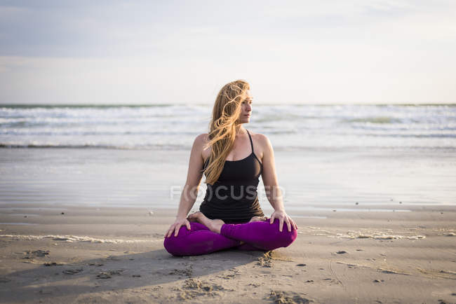 Femme assise sur la plage faisant du yoga dans le Rhode Island le jour du vent — Photo de stock