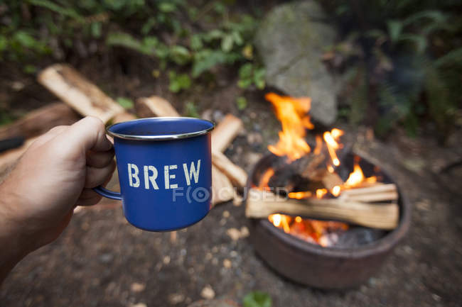 A Camper Enjoying A Mug Of A Beer While Sitting Around A Campfire — Stock Photo