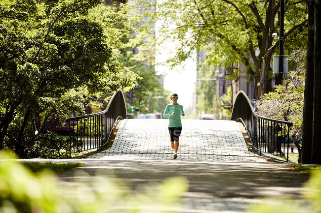 Une femme qui court sur un pont le long de la rivière Charles à Boston — Photo de stock