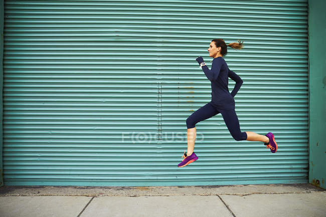 Joggeuse courir et sauter contre le mur vert, Boston, Massachusetts, USA — Photo de stock