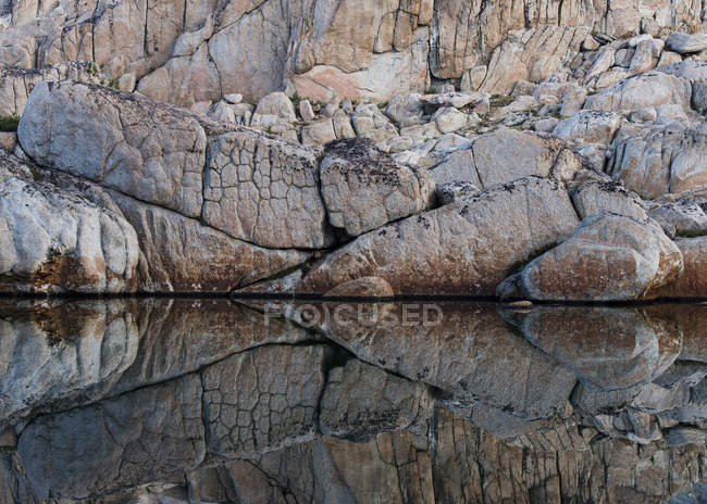 Cracked rocks reflection in lake water — Stock Photo