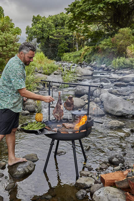 Homem chef cozinhar carne bbq no fogo da floresta — Fotografia de Stock