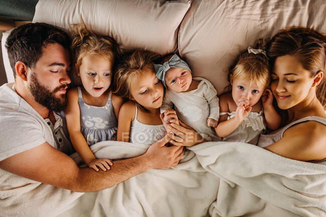 Grande famiglia che posa a letto con molti bambini e si tiene per mano — Foto stock