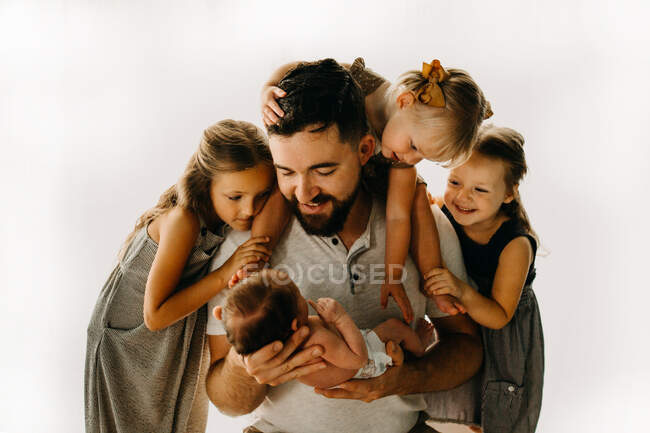 Pai e filhas olhando para o bebê recém-nascido irmão e sorrindo — Fotografia de Stock