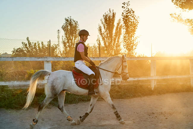 Kind reitet Pferd im Reitunterricht, mit Schutzausrüstung — Stockfoto