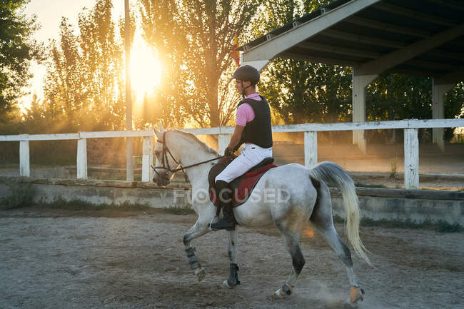 Kid monta a caballo en clase de equitación, con objetos de protección - foto de stock