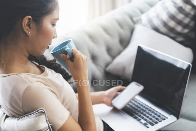 Женщина работает на ноутбуке и пьет кофе — стоковое фото