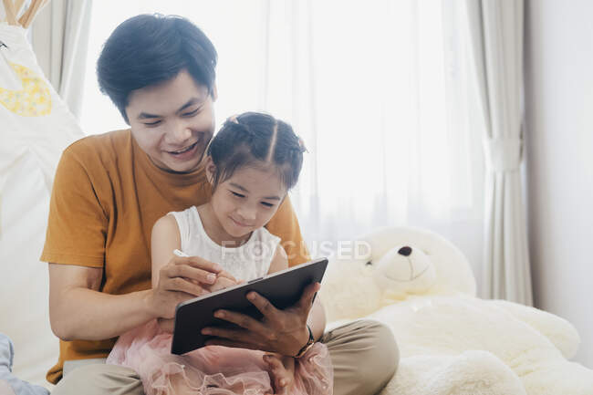 Маленька дівчинка і молодий батько використовують планшет разом — стокове фото