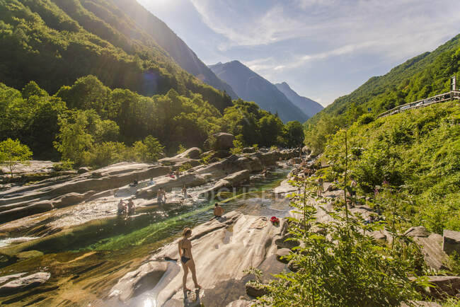 Personas nadando y tomando el sol en el río Verzasca en verano - foto de stock