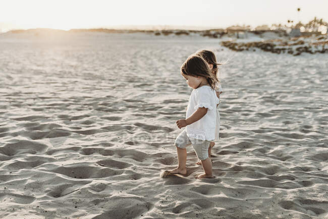 Side view of young toddler girls holding hands and walking at beach — Stock Photo