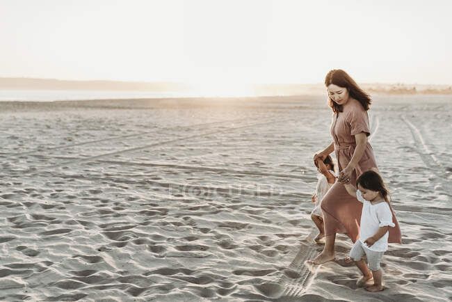 Madre a piedi con 2 anni ragazza in spiaggia durante il tramonto — Foto stock