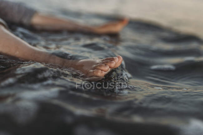 Vista detalhada dos dedos dos pés da criança na água na praia — Fotografia de Stock