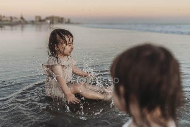 Счастливая 2-летняя девочка плескалась в воде на пляже — стоковое фото