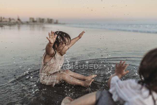Счастливая 2-летняя девочка плескалась в океанской воде на пляже — стоковое фото