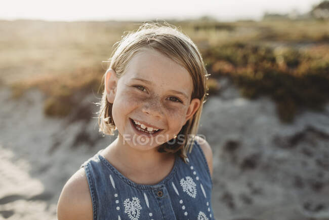 Portrait of young school age girl with freckles smiling on beach — Stock Photo