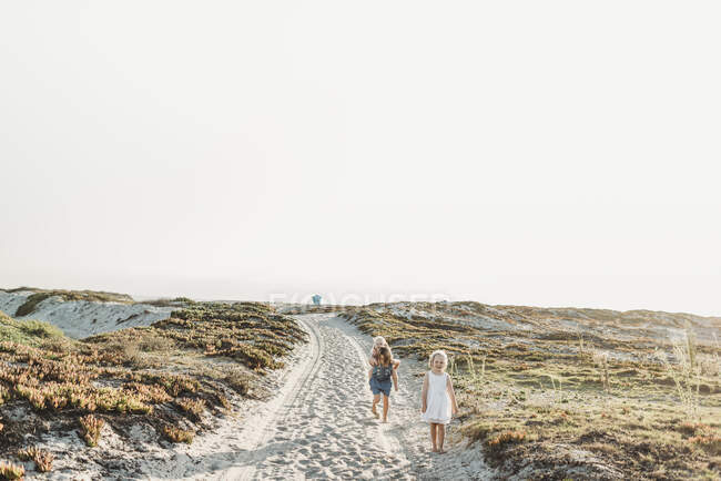Jovens irmãs brincando na areia na praia durante o pôr do sol — Fotografia de Stock