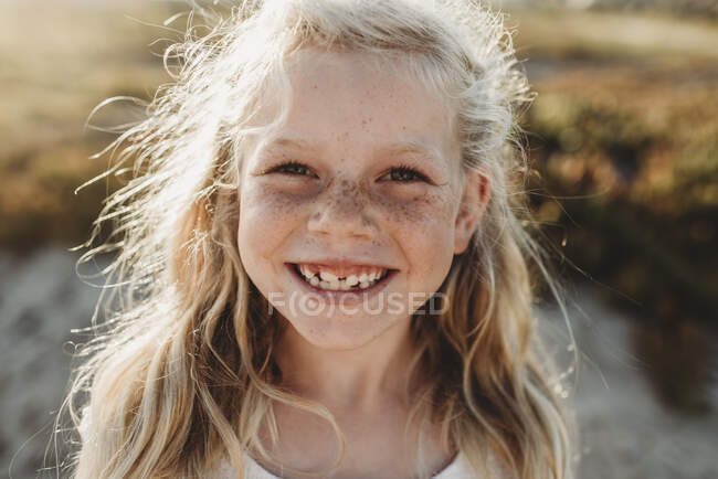 Portrait of young school age girl with freckles smiling at camera — Stock Photo