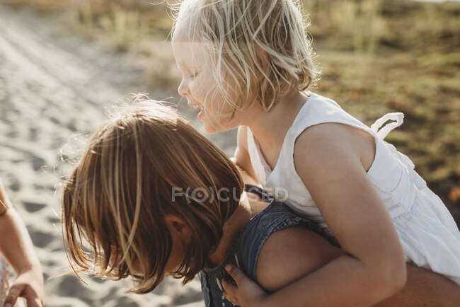 Младшие сестры играют на песке на пляже во время заката — стоковое фото