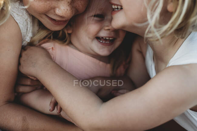 Крупный план малыша, смеющегося в окружении юных сестёр — стоковое фото