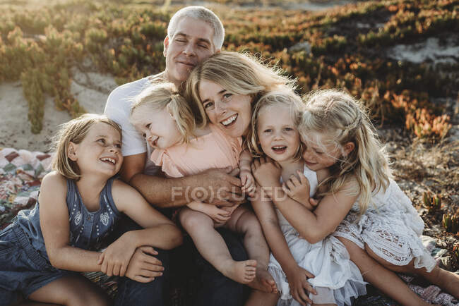 Стиль життя крупним планом сім'ї з молодими сестрами, що сидять на пляжі — стокове фото