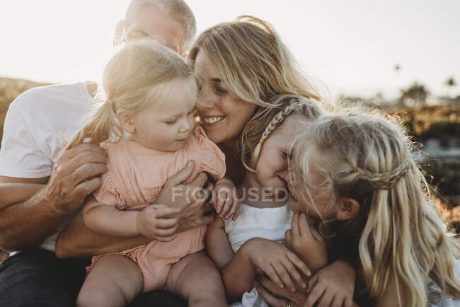 Estilo de vida de cerca de la familia con hermanas jóvenes sentadas en la playa - foto de stock