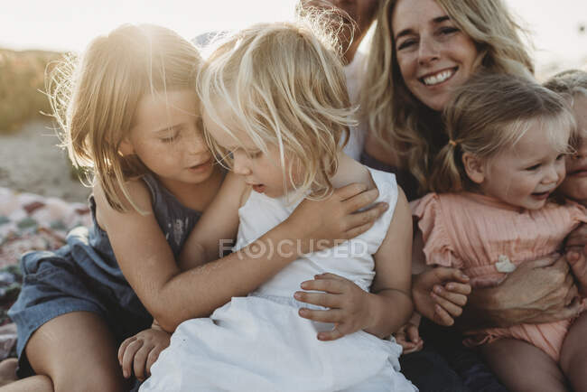 Live рядом с семьей с маленькими сестрами, сидящими на пляже — стоковое фото