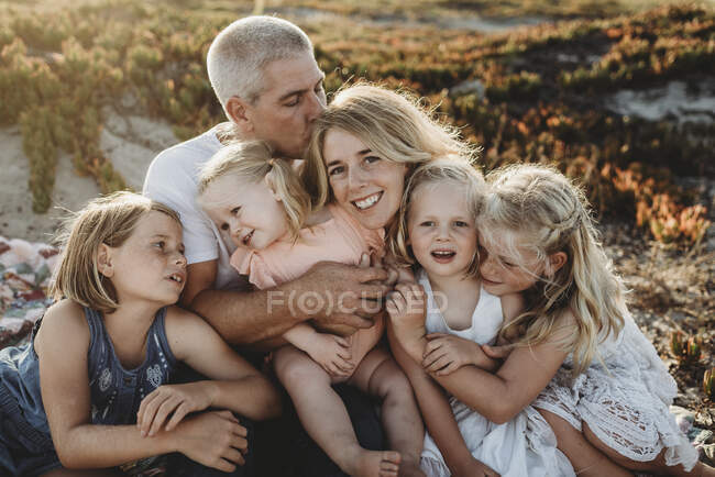 Estilo de vida de cerca de la familia con hermanas jóvenes sentadas en la playa - foto de stock