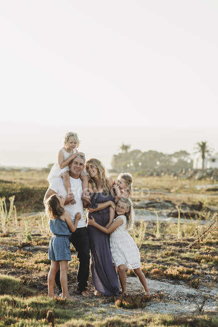 Portrait de famille avec des jeunes filles souriant au coucher du soleil sur la plage — Photo de stock