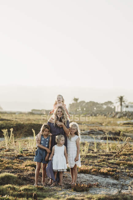 Lifestyle portrait of mother with young girls smiling at beach sunset — Stock Photo