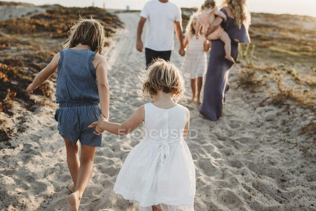 Молодая девочка дошкольного возраста держит за руки свою сестру и уходит. — стоковое фото