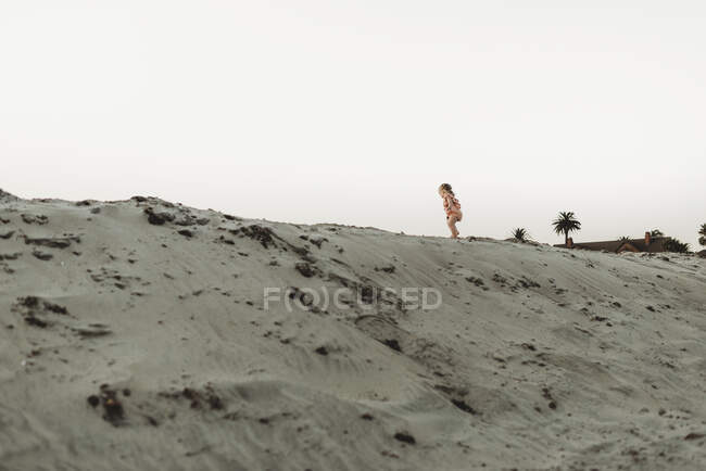 Wide view of toddler girl walking in sand at beach — Stock Photo