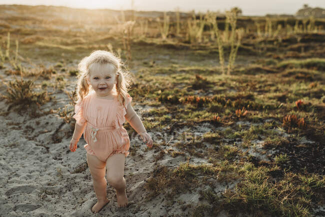 Ritratto di bambina con le trecce che sorride alla telecamera sulla spiaggia — Foto stock